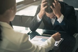Stressed out man in meeting with professional, looking at charts