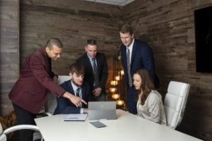 A team of five professionals working at a computer.