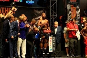 a boxer at the podium surrounded by fight promoters and onlookers