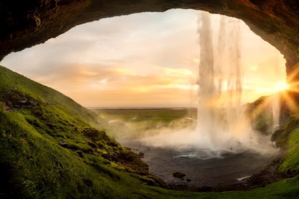 Cave with waterfall and sunrise in the background